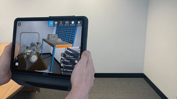 A pair of hands holding a tablet using the Theorem-AR app to visualize multiple models in Augmented Reality.