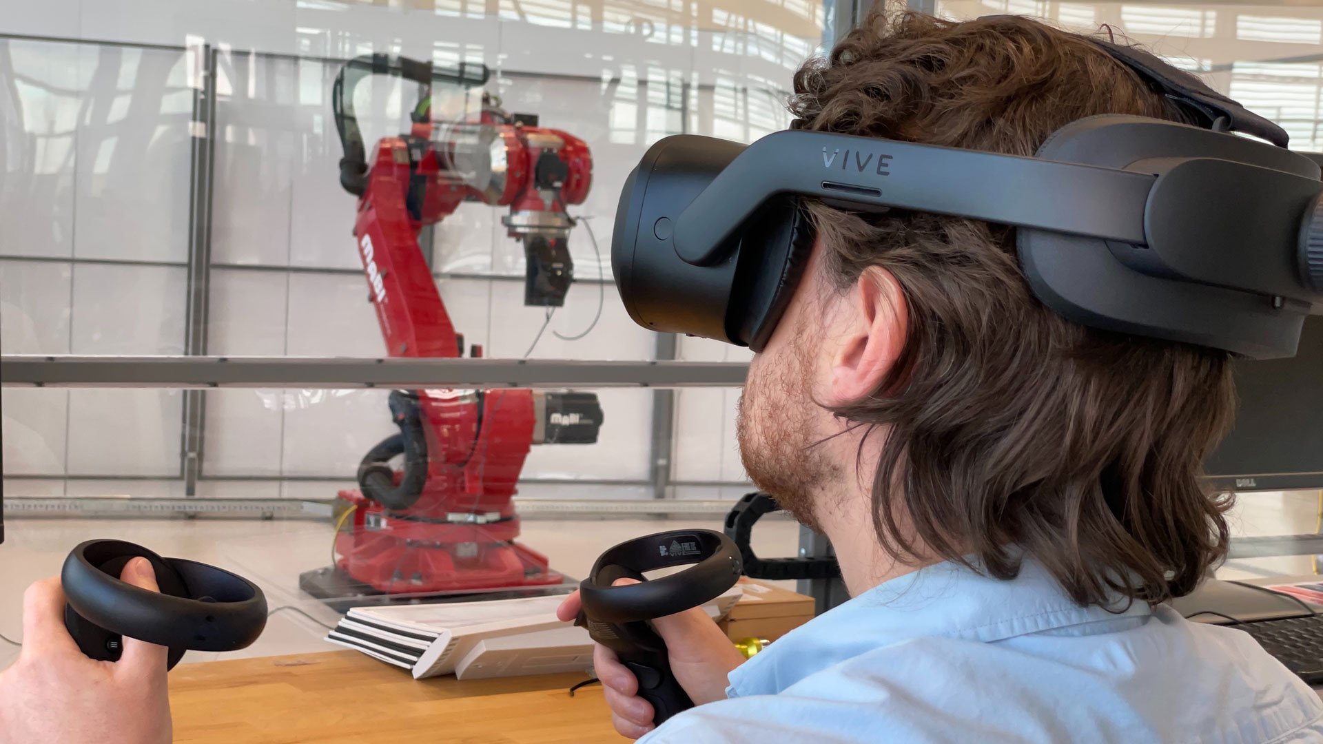 Engineer working in VR next to a robot work cell